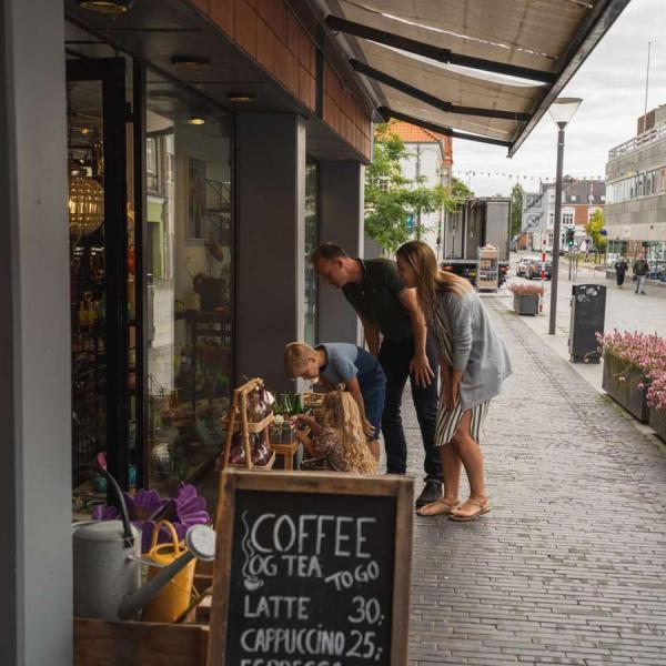 Familie på shopping kigger på varer uden for butik i Odder by - en del af Destination Kystlandet