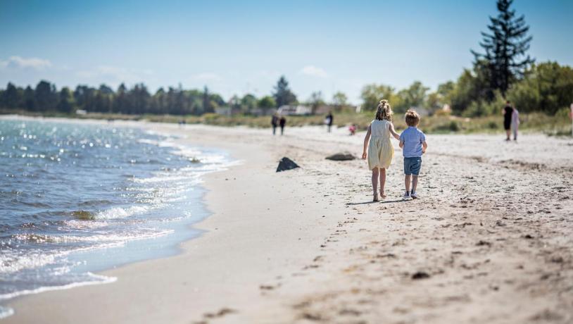 Børn går på stranden ved Saksild