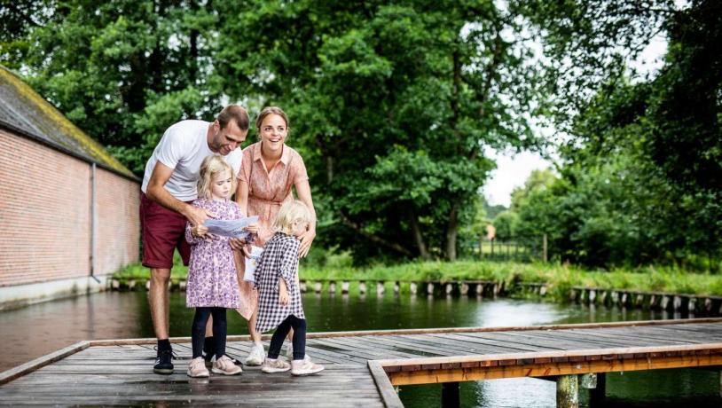 Familie på skattejagt på træbro over vandløb i Odder - en del af Destination Kystlandet