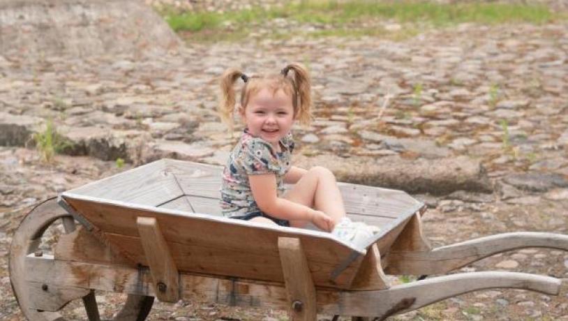 brosten på gårdsplads med barn i trillebøre og hvid gård i baggrunden