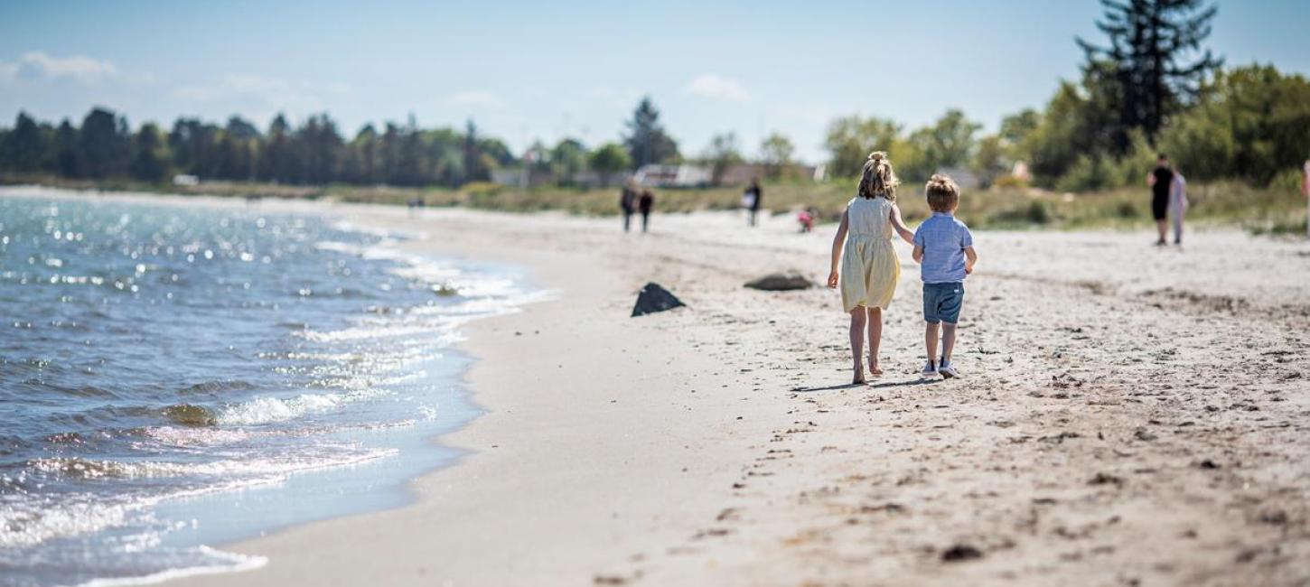 Børn går på stranden ved Saksild