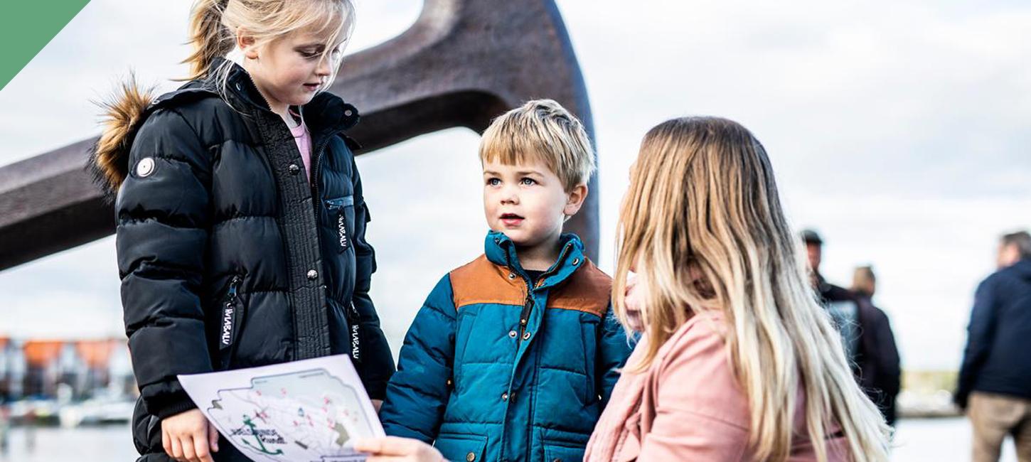 Mor og to børn kigger på skattekort foran ankeret i Juelsminde