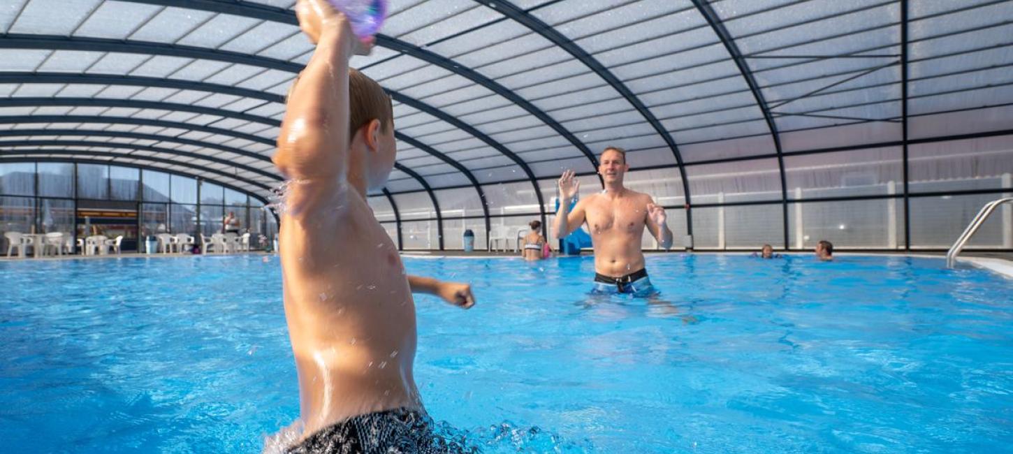 En dreng og en far spiller bold i en pool ved Horsens City Camping ved Husodde i Destination Kystlandet