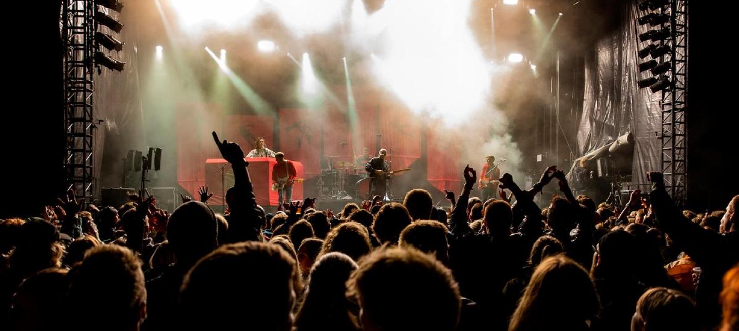 hænder i luften foran en scene om aftenen til wall of sound i Destination Kystlandet