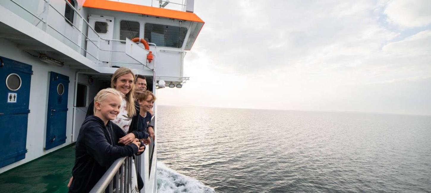 Familie på dækket som kigger ud over vandet på overfarten fra Snaptun til Endelave med Endelavefærgen