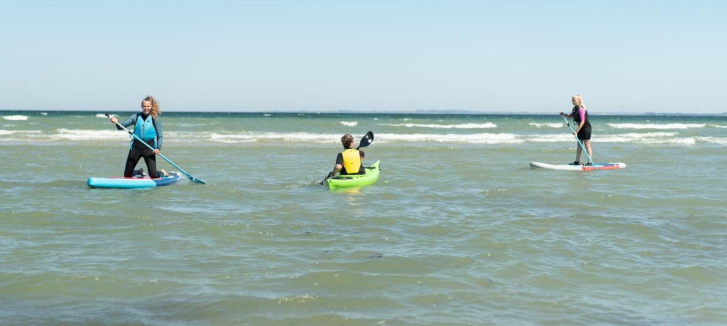 Women on SUP-boards and a man in a sea kayak at Saksild Beach