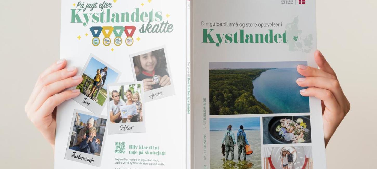 En kvinde læser i en feriebrochure til turister om Destination Kystlandet