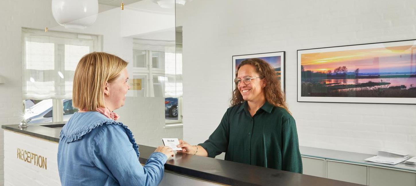 Receptionist giver visitkort til 