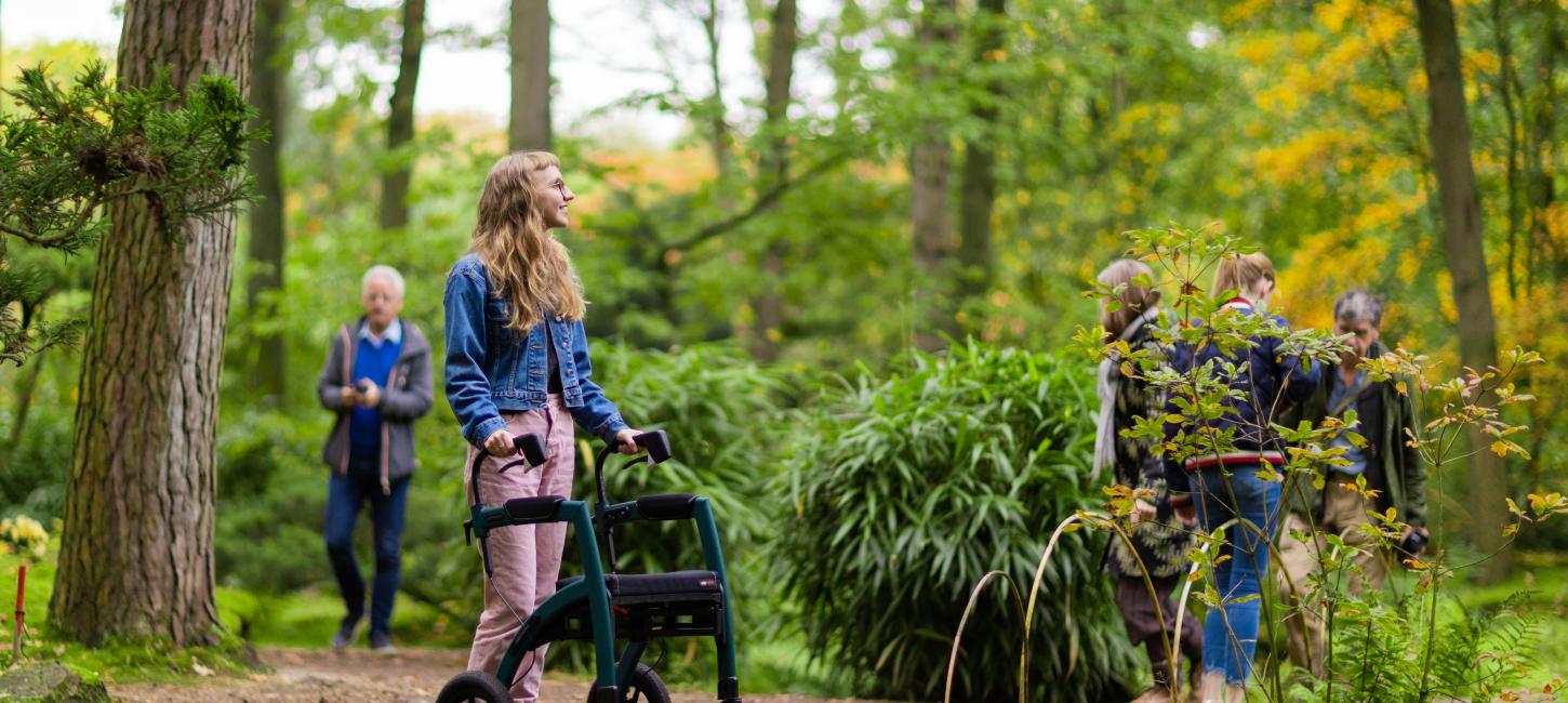 kvinde står i skov med rollator