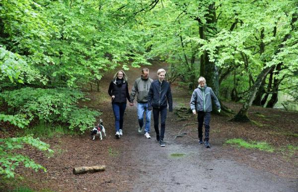 Familie går tur med hund i skoven