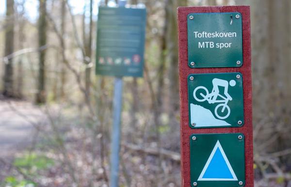 Skilt for blåt spor på mountainbikeruten i Tofteskoven i Juelsminde