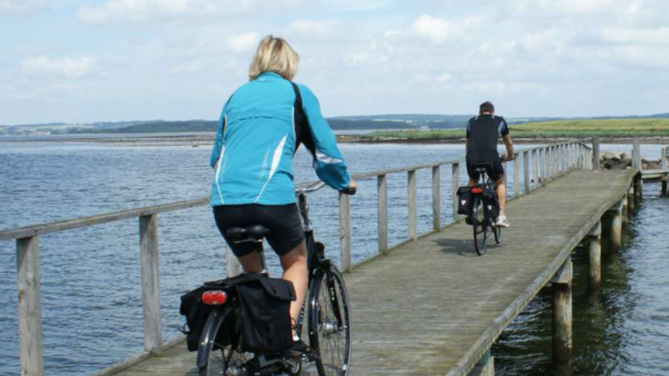 To cyklister cykler ud af en badebro