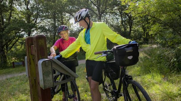 Ældre par på cykeltur kigger på skilt ved Gudenåens udspring