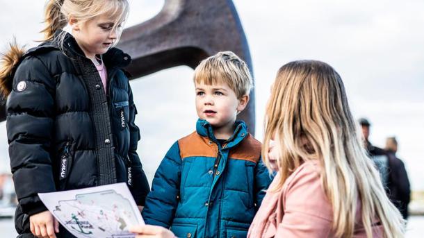 Mor og to børn kigger på skattekort foran ankeret i Juelsminde