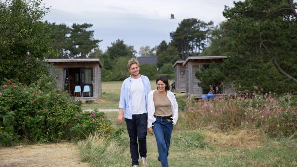 Par går mod stranden foran hytte på Tunø Teltplads i Destination Kystlandet