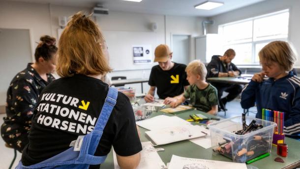 Børn og familier sidder ved et bord og tegner på Kulturstationen i Horsens, Destination Kystlandet