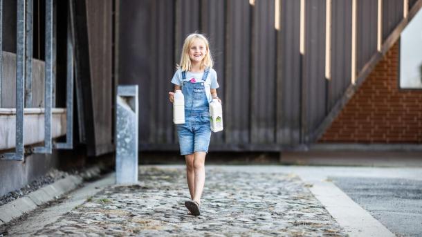 Lille pige bærer på to liter mælk ved Vejlskovgaard mælketapperi i Destination Kystlandet