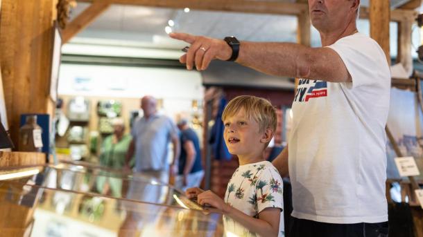 Dreng og hans far kigger på skibsudstilling på Juelsminde Havnemuseum