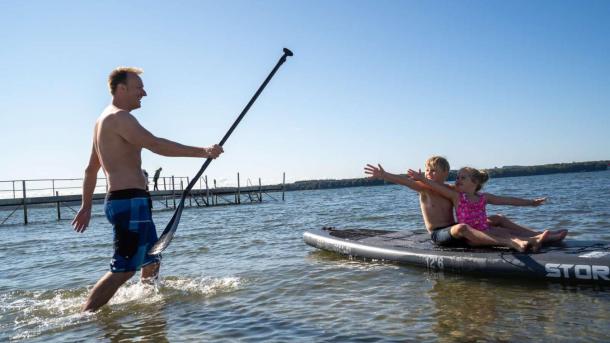 Children sitting on an SUP-board at Husodde Beach