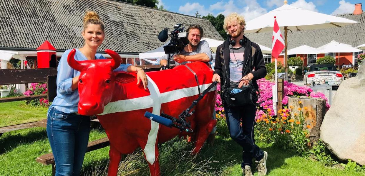TV-hold står foran en rød ko ved Café Alrø 