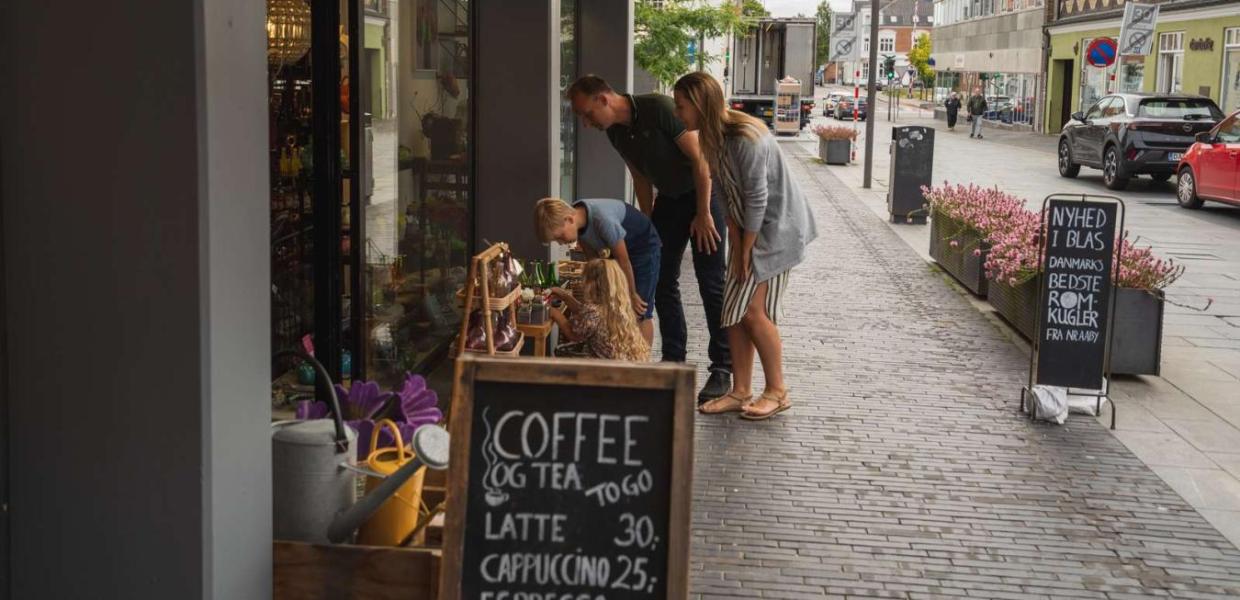 Familie på shopping kigger på varer uden for butik i Odder by - en del af Destination Kystlandet