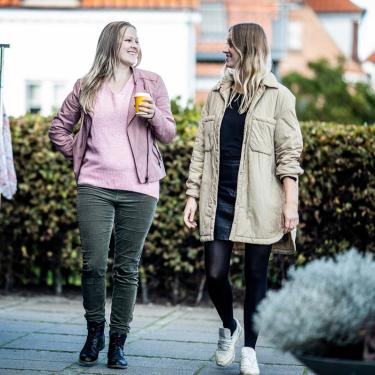 Veninder går og taler ved siden af tøj stativer