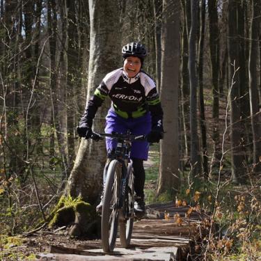 Kvinde cykler på mountainbike på sporet i Tofteskoven i Juelsminde