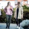 Veninder går og taler ved siden af tøj stativer