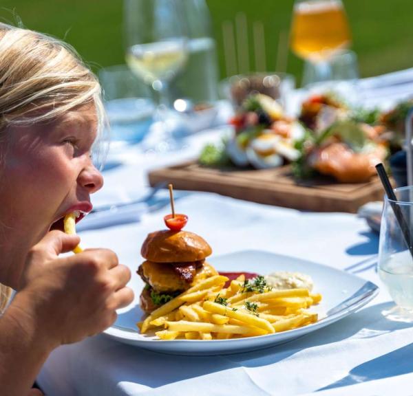 Dreng spiser burger og pommes frites på Mejeriet på Tunø der ligger i Destination Kystlandet