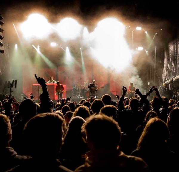 hænder i luften foran en scene om aftenen til wall of sound i Destination Kystlandet