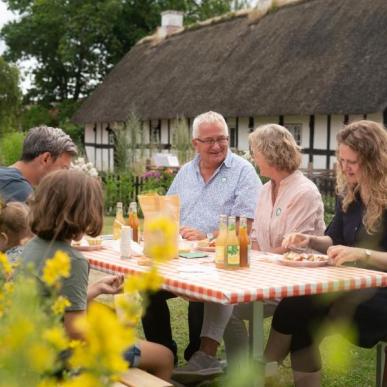 Familie med børn, børnebørn og bedsteforældre spiser frokost ved Glud Museum