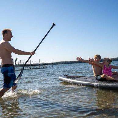 Children sitting on an SUP-board at Husodde Beach