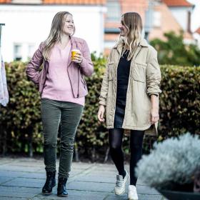 Veninder går og taler ved siden af tøj stativer
