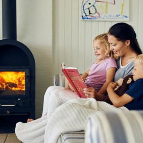 Mor læser højt for to børn i sommerhus i Kystlandet