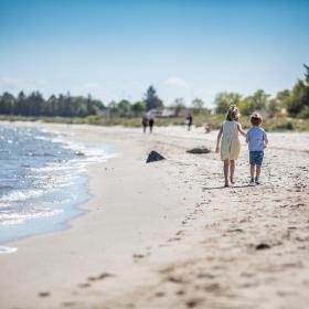 Børn går på stranden ved Saksild