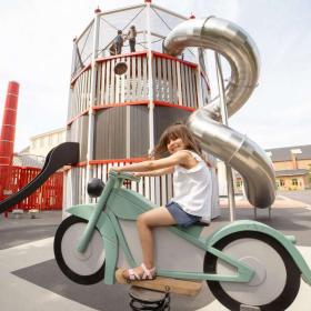 Pige sidder på vippe motorcykel på industrimuseets legeplads