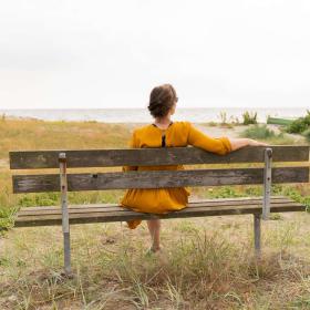 Kvinde sidder på en bænk på storstranden i Juelsminde