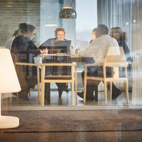 Aktivt møde i mødelokale bag glasvæg på Hotel Opus i Horsens - en del af Destination Kystlandet