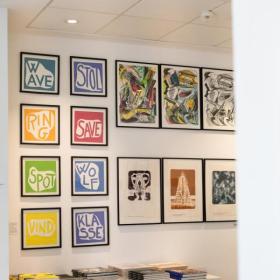 Plakater hænger på væggen i en museumsbutik i Horsens ved Horsens Kunstmuseum i Destination Kystlandet.
