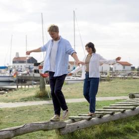 Mand og kvinde balancerer på legepladsen på Tunø Havn - en del af Destination Kystlandet