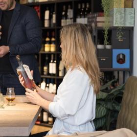 Dame holder en flaske whisky i specialbutikken Water Of Life på Mejeritorvet i Brædstrup