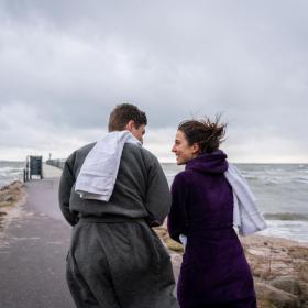 Mand og kvinde er på vej ud at vinterbade ved Hou Strand i Kystlandet