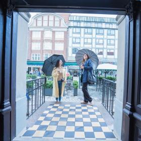 To veninder kigger på Jørgensens Hotel facade i Horsens med paraplyer