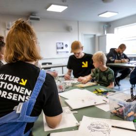 Børn og familier sidder ved et bord og tegner på Kulturstationen i Horsens, Destination Kystlandet