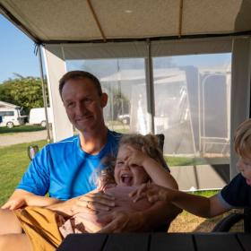 Far med to børn i fortelt ved campingvogn på Horsens City Camping - en del af Destination Kystlandet