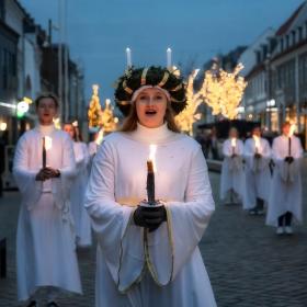 Kvinder i hvide kjoler med lys i hånden til juleaktiviteter og shopping i Destination Kystlandet 