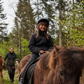 Pige ridder på brun hest med en guide 