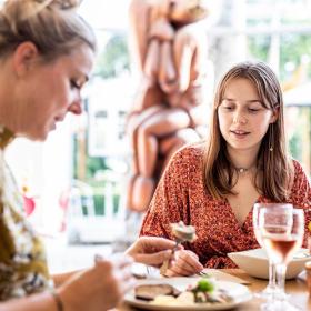 To kvinder spiser frokost i solskin på Horsens Kunstmuseum i Destination Kystlandet