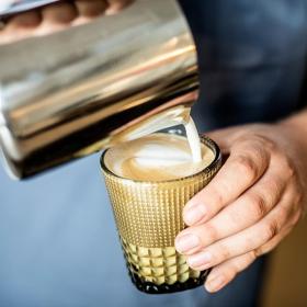 Mand laver latte-art i et brunt glas ved spisestedet og cafeen 8F i Horsens