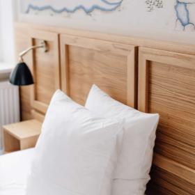 To puder står op af et hovedgærde af træ på en hotelseng 